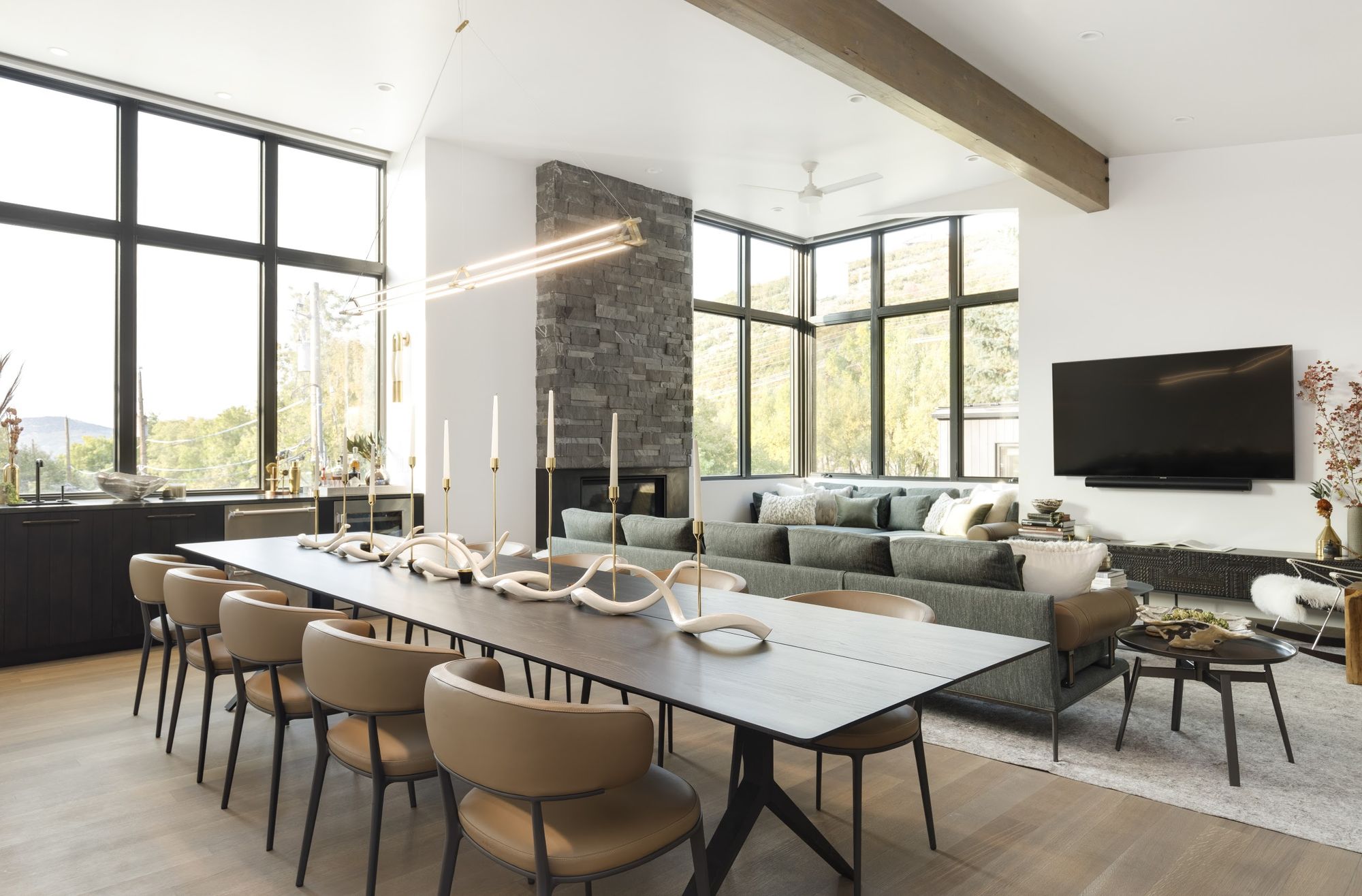 Open living and dining level with a twelve-seat table, stone fireplace and floor-to-ceiling windows
